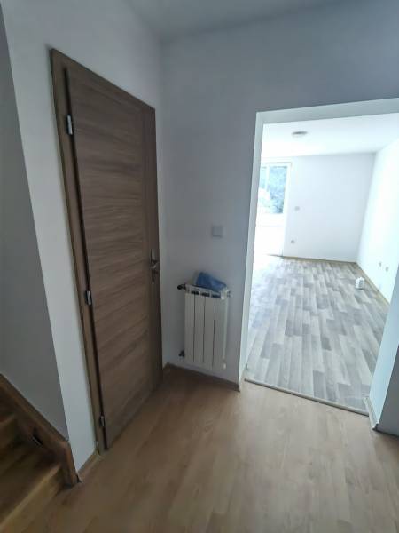 PREDAJ – 4-izbový rodinný dom v radovej zástavbe s garážou - Interiér rodinného domu s dverami, radiátorom a podlahou s dreveným dekorom.