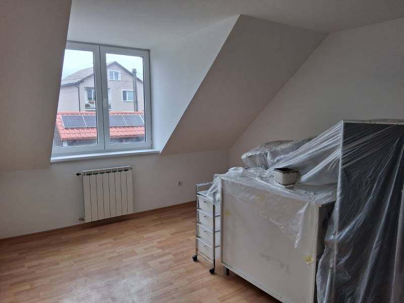 PREDAJ – 4-izbový rodinný dom v radovej zástavbe s garážou - Miestnosť v rodinnom dome s oknom, vykurovacím telesom a podlahou s dreveným dekorom.