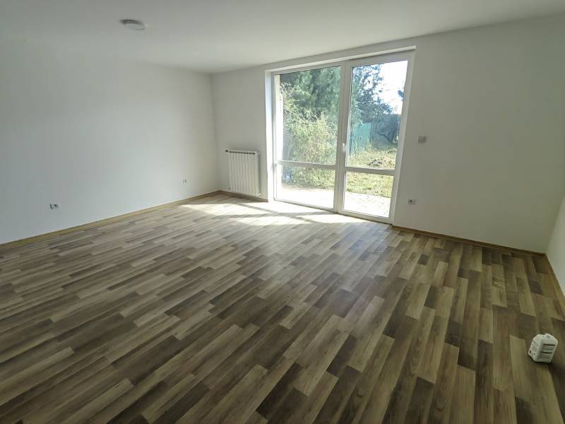 PREDAJ – 4-izbový rodinný dom v radovej zástavbe s garážou - Priestranná miestnosť s podlahou s dreveným dekorom a veľkým oknom v rodinnom dome.