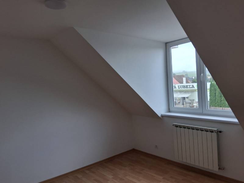 PREDAJ – 4-izbový rodinný dom v radovej zástavbe s garážou - Pokoj pod strechou s oknom a podlahou s dreveným dekorom v rodinnom dome.