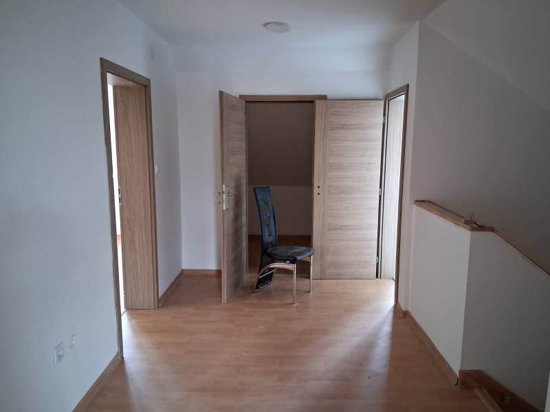 PREDAJ – 4-izbový rodinný dom v radovej zástavbe s garážou - Izba v rodinnom dome s podlahou s dreveným dekorom a tromi drevenými dverami.