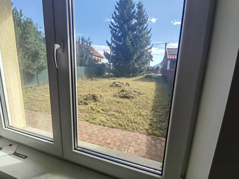 PREDAJ – 4-izbový rodinný dom v radovej zástavbe s garážou - Pohľad z rodinného domu v Ľubeli do záhrady s udržiavaným trávnikom a stromami.