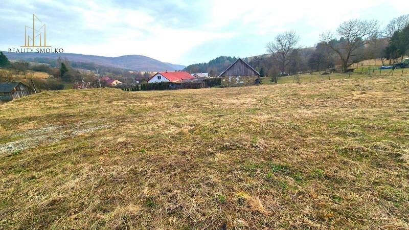 Na predaj POZEMOK na výstavbu rodinného domu - 3346 m², Kečkovce - Pozemky - bývanie v Kečkovciach, trávnaté pole s vidieckymi domami a kopcovitou krajinou.