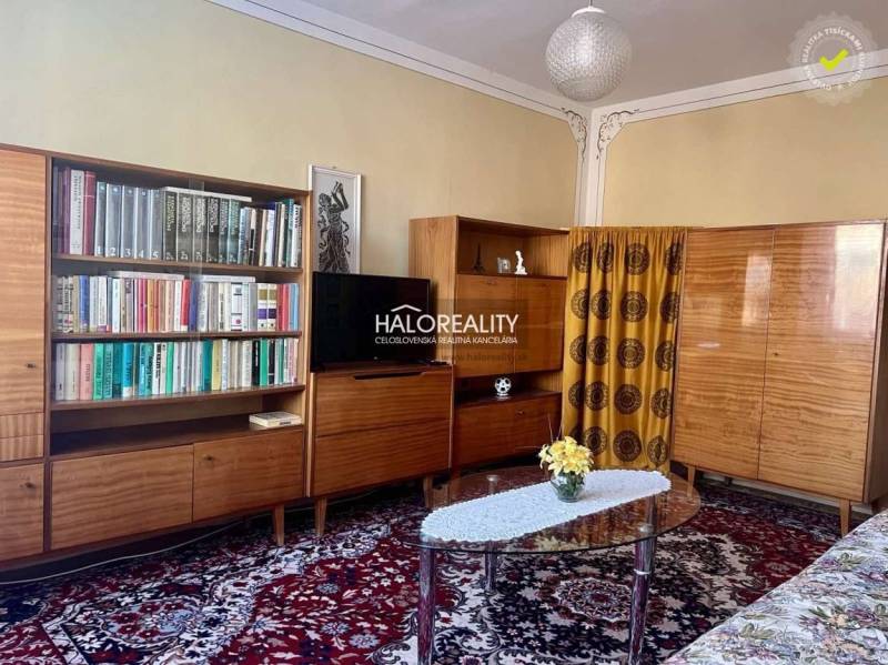 REZERVOVANÉ - Predaj, trojizbový byt Bojnice, Lúčky ... - Obývacia izba v 3-izbovom byte s knihovňou, televízorom a kobercom s kvetinovým vzorom.