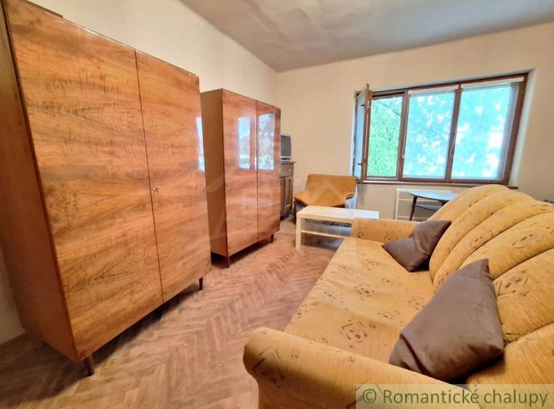 Pôvodný domček v obci Nová Vieska - Obývacia izba v rodinnom dome so skriňami, podlahou s dreveným dekorom a pohovkou.