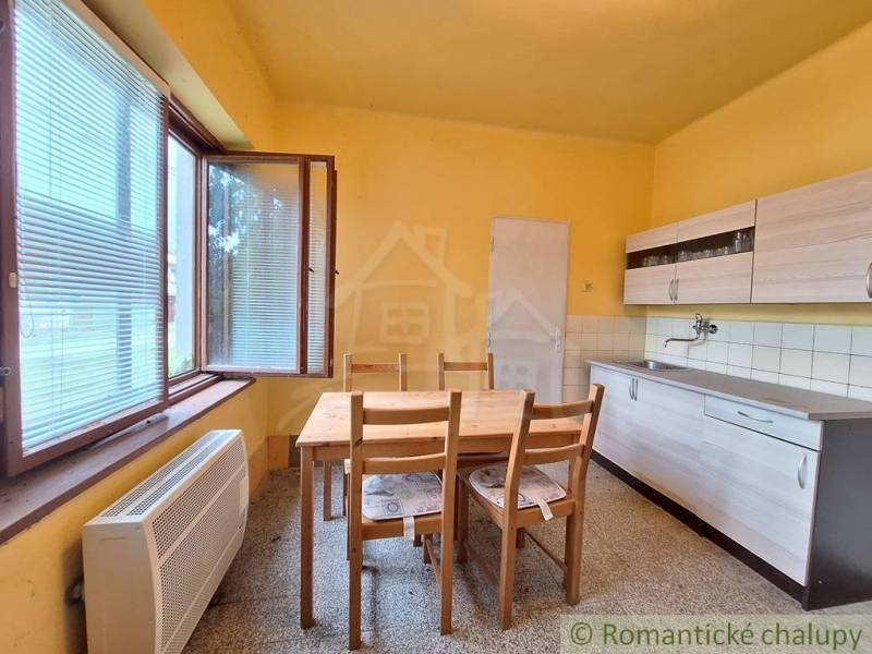 Pôvodný domček v obci Nová Vieska - Kuchyňa v rodinnom dome s dreveným stolom, oknom a skrinkami.