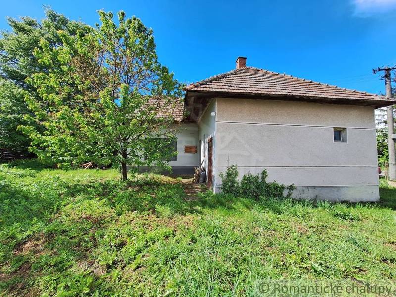 Pôvodný domček v obci Nová Vieska - Rodinný dom v Novej Vieske obkolesený zeleňou a stromami, s tradičnou strechou.