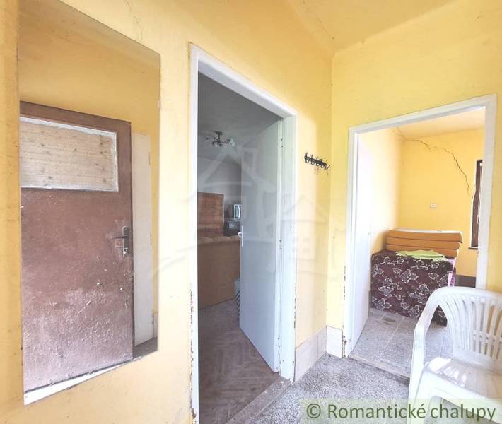 Pôvodný domček v obci Nová Vieska - Žlté steny, vstupná chodba, izby, nábytok, plastová stolička v rodinnom dome.