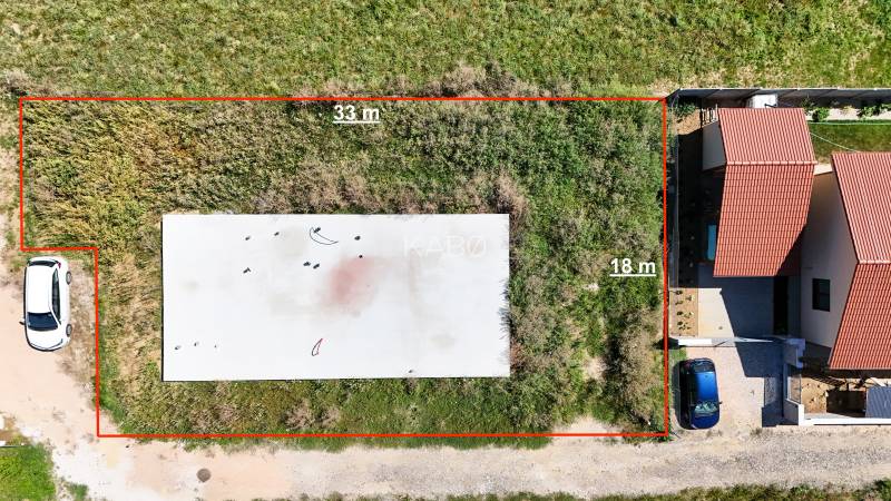 Základová doska na  575 m2 pozemku - Čeľadice  - Pozemky - bývanie v Čeľadiciach: zobrazuje oplotený trávnatý pozemok so stavbou.