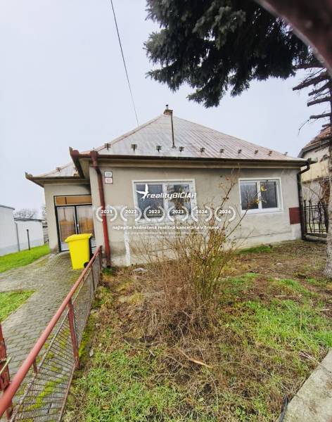 Predaj rodinného domu, Seredská, Seredská, Hlohovec - Rodinný dom na Seredskej ulici v Hlohovci, záhrada, živý plot, strom, žltý kontajner.