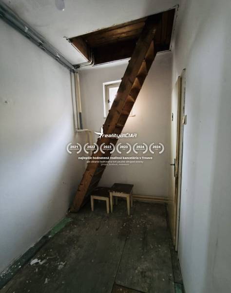 Predaj rodinného domu, Seredská, Seredská, Hlohovec - Úzka izba s dreveným schodiskom a oknom v rodinnom dome.