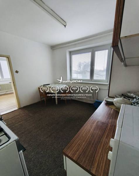 Predaj rodinného domu, Seredská, Seredská, Hlohovec - Kuchyňa s plynovým sporákom a kobercom v Rodinnom dome, biely interiér, stôl, okno so žalúziami.