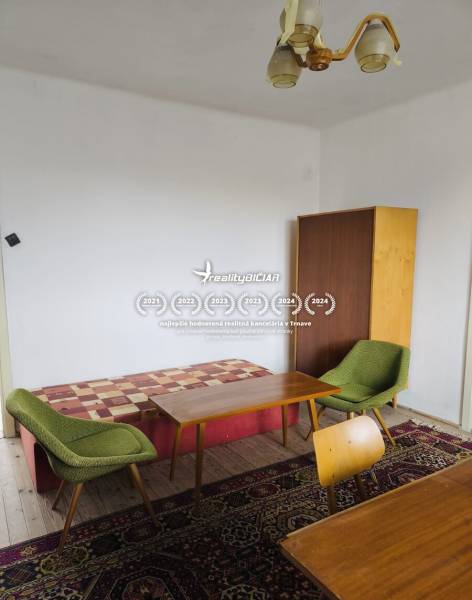 Predaj rodinného domu, Seredská, Seredská, Hlohovec - Izba rodinného domu s kreslami, stolmi, skrinkou a podlahou s dreveným dekorom.