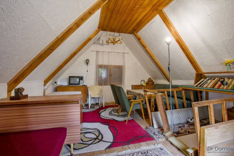 NA PREDAJ CHATA V REKREAČNEJ OBLASTI RUDAVA, OBEC MALÉ LEVÁRE - Podkrovie s drevenými trámami, kobercom a starožitným televízorom v chate.
