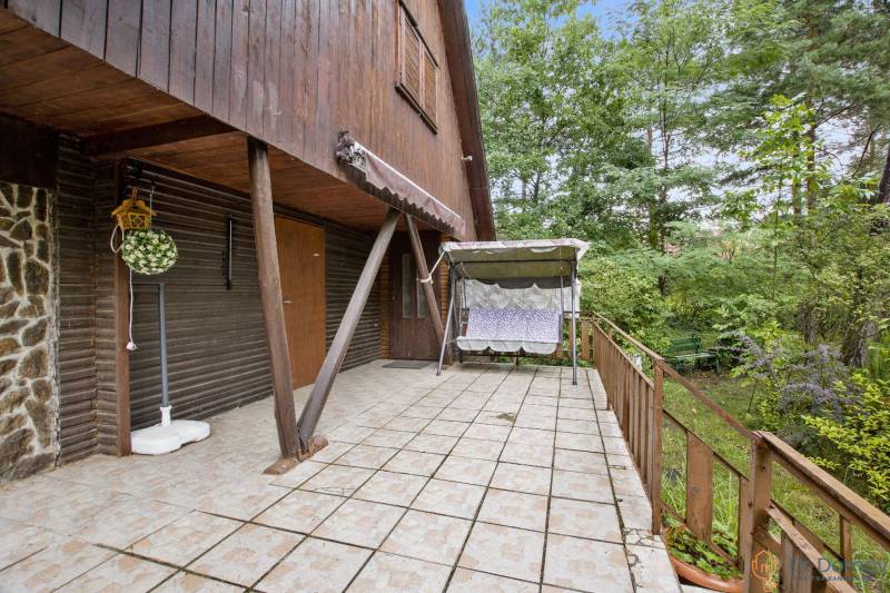 NA PREDAJ CHATA V REKREAČNEJ OBLASTI RUDAVA, OBEC MALÉ LEVÁRE - Terasa pri chate v Malých Levároch s hojdacou lavicou a bohatou zeleňou.