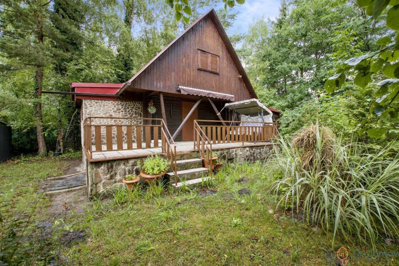 NA PREDAJ CHATA V REKREAČNEJ OBLASTI RUDAVA, OBEC MALÉ LEVÁRE - Chata v Malých Levároch s kamennou terasou obklopená zeleňou a stromami.