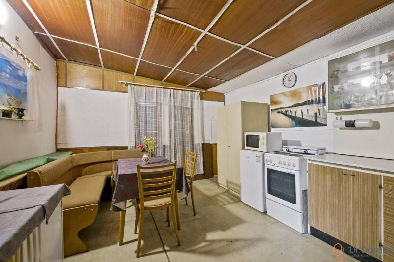 NA PREDAJ CHATA V REKREAČNEJ OBLASTI RUDAVA, OBEC MALÉ LEVÁRE - Interiér chaty s kuchynským kútom, rohovou lavicou a jedálenským stolom.