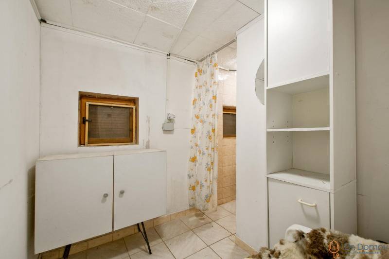 NA PREDAJ CHATA V REKREAČNEJ OBLASTI RUDAVA, OBEC MALÉ LEVÁRE - Interiér chaty s dlažbou, skrinkou a kvetinovým závesom v sprchovom kúte.