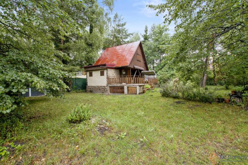 NA PREDAJ CHATA V REKREAČNEJ OBLASTI RUDAVA, OBEC MALÉ LEVÁRE - Chata v Malých Levároch obklopená zeleňou, s červenou strechou a drevenými prvkami.