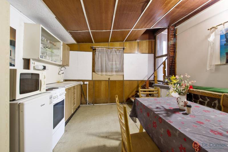 NA PREDAJ CHATA V REKREAČNEJ OBLASTI RUDAVA, OBEC MALÉ LEVÁRE - Kuchyňa v Chate s kuchynskou linkou, stolom a stoličkami, podlaha s dreveným dekorom.