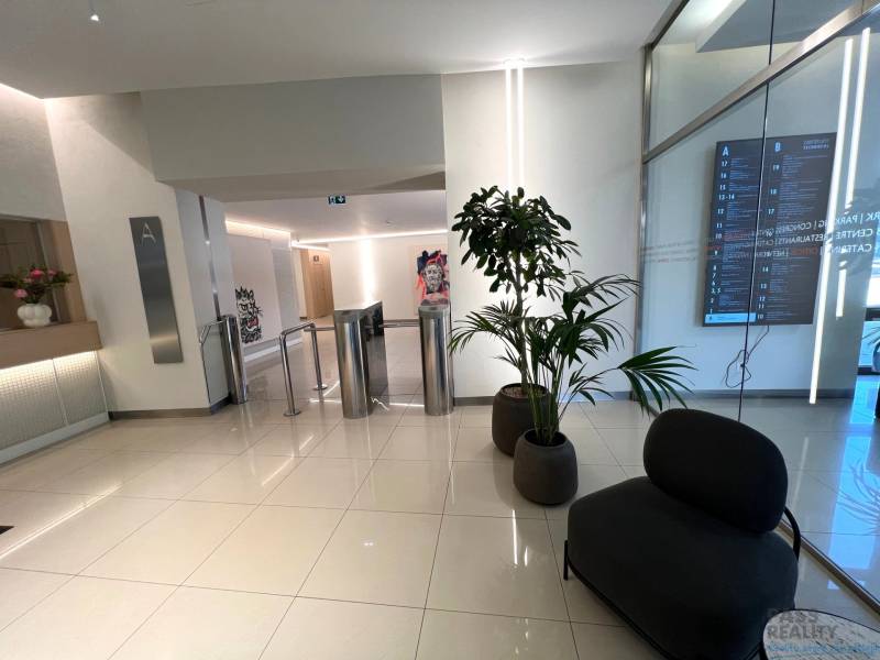 PRENÁJOM exkluzívnych priestorov 318 m2 TECHNOPOL, Kutlíkova ul. - Interiér obchodných priestorov s turniketmi, kvetmi a moderným nábytkom na podlahe s dekorom.