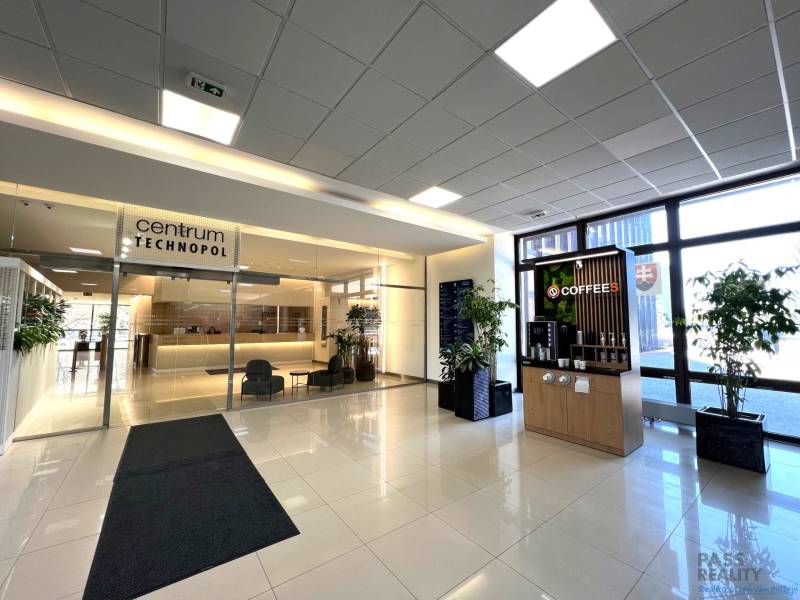 PRENÁJOM exkluzívnych priestorov 318 m2 TECHNOPOL, Kutlíkova ul. - Interiér obchodných priestorov s recepciou, stolmi, kávovarom a rastlinami.