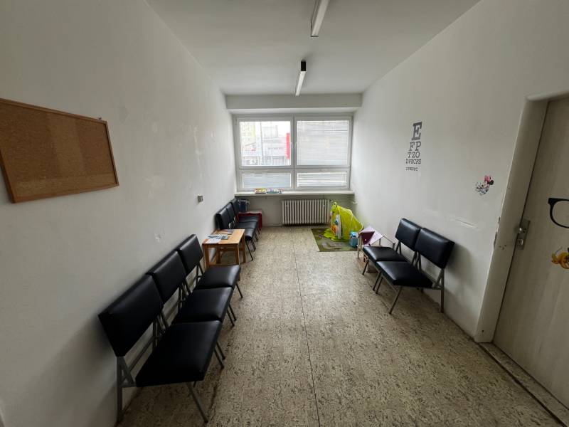 Prenájom ordinácie v zdravotnom stredisku Saratovská 24, Bratislava. - Čakáreň s čiernymi stoličkami, detským kútikom a svetlou podlahou v obchodných priestoroch.