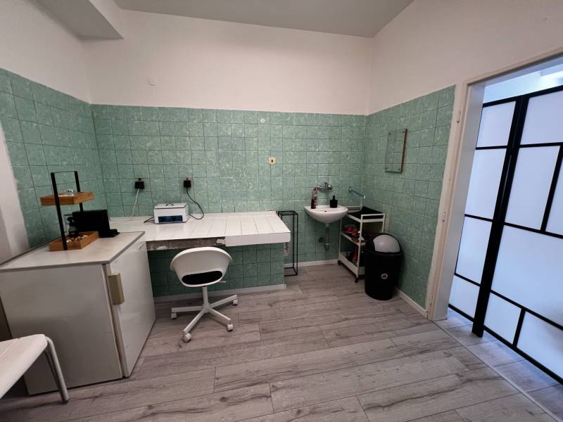 Prenájom ordinácie v zdravotnom stredisku Saratovská 24, Bratislava. - Interiér obchodných priestorov so zelenými obkladačkami a podlahou s dreveným dekorom.