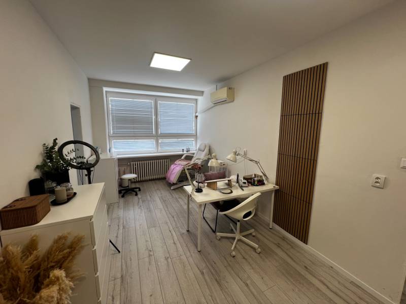 Prenájom ordinácie v zdravotnom stredisku Saratovská 24, Bratislava. - Interiérový priestor s pracovným stolom, stoličkou a podlahou s dreveným dekorom.