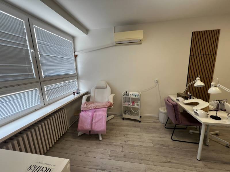 Prenájom ordinácie v zdravotnom stredisku Saratovská 24, Bratislava. - Kozmetický salón s kreslom, stolíkom a podlahou s dreveným dekorom v obchodných priestoroch.