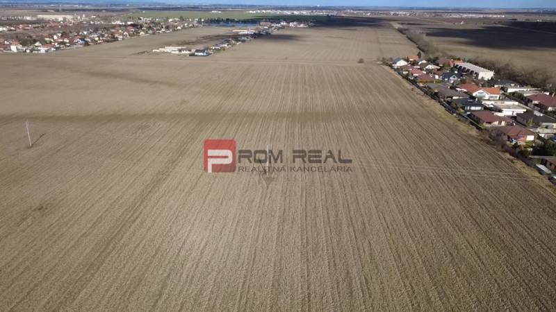 INVESTIČNÁ PRÍLEŽITOSŤ – Pozemok v obci Dunajská Lužná - Rozľahlé poľnohospodárske a lesné pozemky v okolí Dunajskej Lužnej, s viditeľnou obytnou zástavbou.