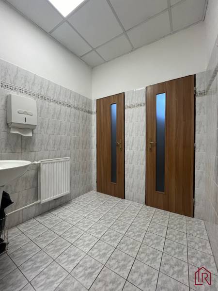 Investičná príležitosť: Polyfunkčná budova 1 000m², Košice-Staré mesto - Kúpeľňový interiér v budove s dvierkami, umývadlom a svetlou dlažbou.