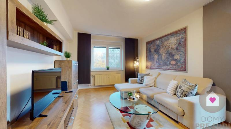 BA/STARÉ MESTO - Prenájom kompletne zariadeného 2i bytu s 2 balkónmi - Obývacia izba v 2-izbovom byte s pohovkou, TV a podlahou s dreveným dekorom.