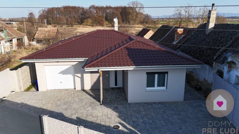 MALÉ LEVÁRE-Predaj  3i modernej novostavby RD s tep. čerpadlom + garáž - Rodinný dom na ulici Malé Leváre v Malých Levároch s červenou strechou a dláždeným dvorom.
