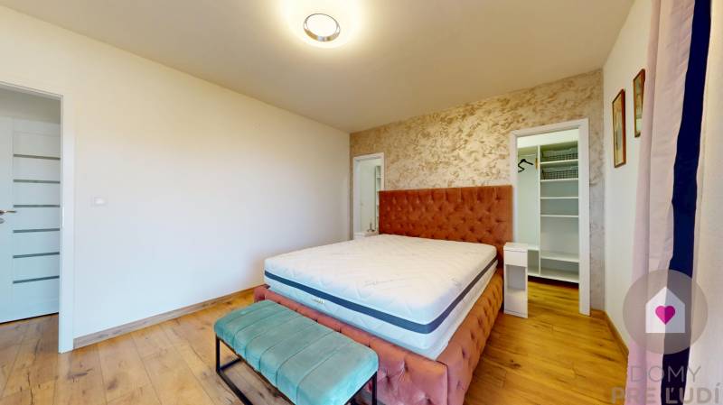 MALÉ LEVÁRE-Predaj  3i modernej novostavby RD s tep. čerpadlom + garáž - Spálňa v rodinnom dome s posteľou, čalúneným čelom a podlahou s dreveným dekorom.