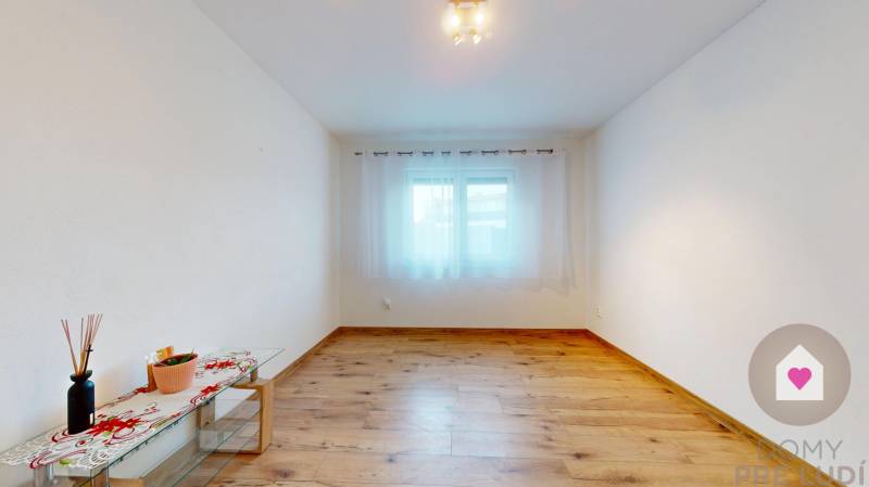 MALÉ LEVÁRE-Predaj  3i modernej novostavby RD s tep. čerpadlom + garáž - Izba s podlahou s dreveným dekorom, bielymi stenami a oknom v rodinnom dome.