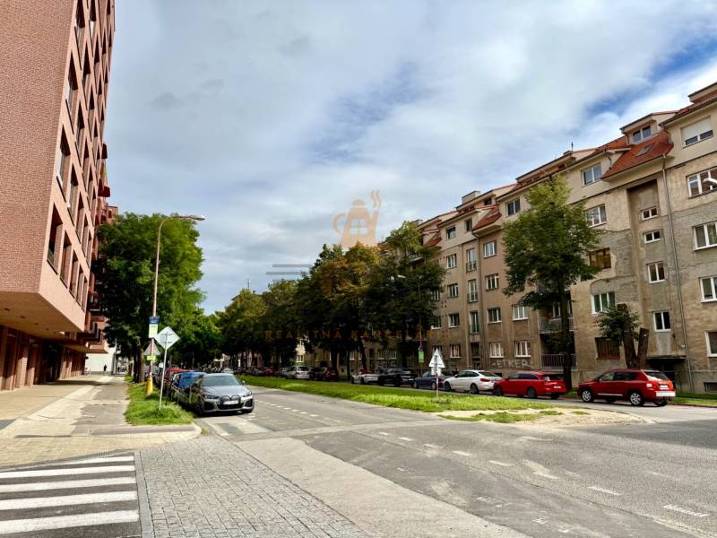PRENÁJOM 1 izbový byt, 40 M2, Bratislava, Ružinov, Košická ulica, NIVY - Ulica v Bratislave - Ružinove so zaparkovanými autami a obytnými budovami.