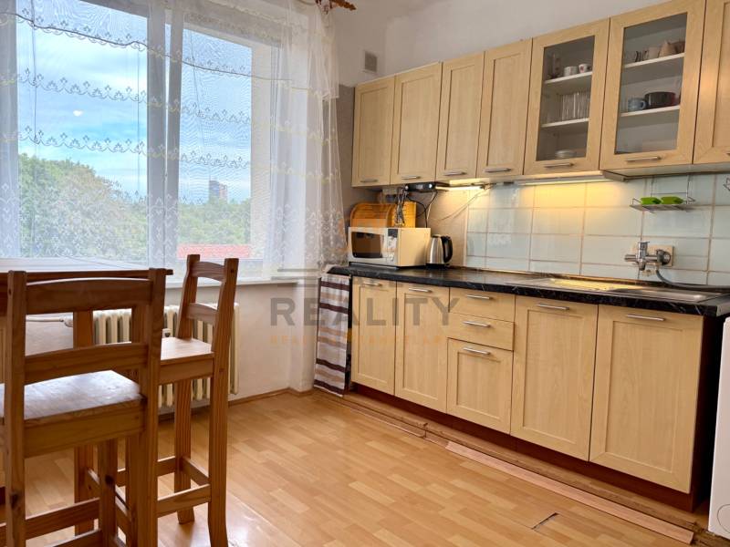 PRENÁJOM 1 izbový byt, 40 M2, Bratislava, Ružinov, Košická ulica, NIVY - Kuchyňa v 1-izbovom byte s podlahou s dreveným dekorom a veľkým oknom.