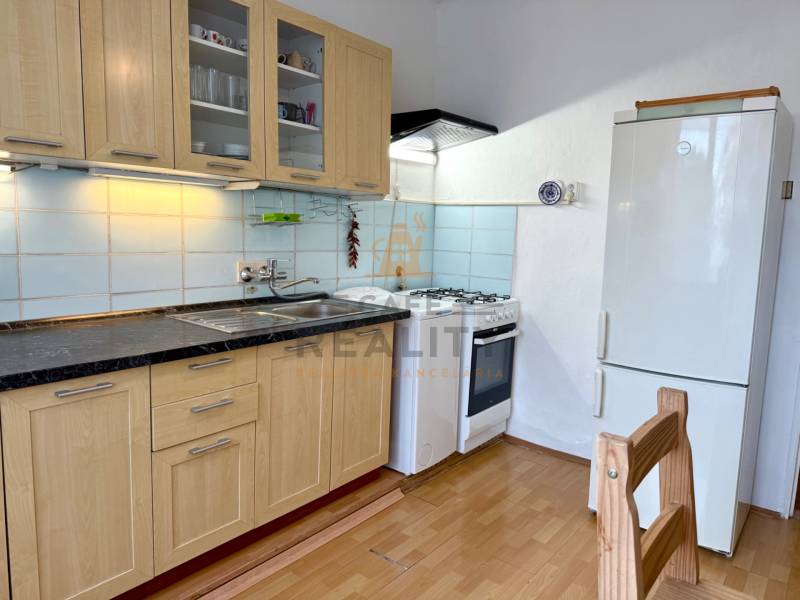 PRENÁJOM 1 izbový byt, 40 M2, Bratislava, Ružinov, Košická ulica, NIVY - Kuchyňa v 1-izbovom byte s dreveným dekorom, kuchynskou linkou a spotrebičmi.