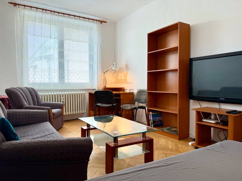 PRENÁJOM 1 izbový byt, 40 M2, Bratislava, Ružinov, Košická ulica, NIVY - Obývacia izba v 1-izbovom byte s pohovkou, stolíkom a podlahou s dreveným dekorom.