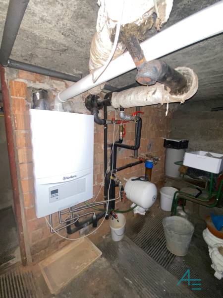 RD so záhradou, pivnicou garážou na Myjave.  - Plynový kotol v pivnici rodinného domu s potrubím a zásobníkom vody na stene.