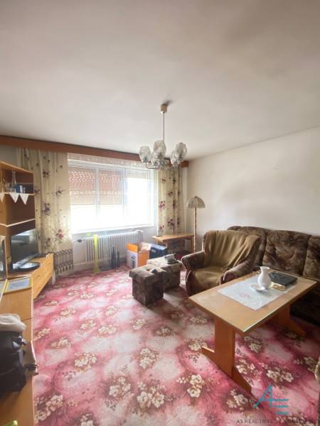 RD so záhradou, pivnicou garážou na Myjave.  - Obývacia izba v rodinnom dome s kobercom s kvetinovým vzorom a nábytkom.