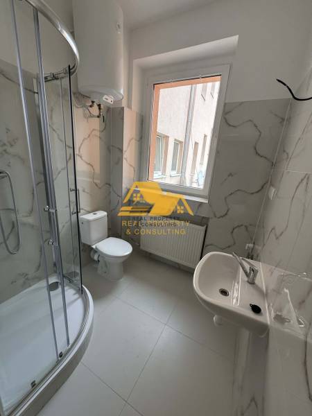 Prenajmem 1 izbový byt v Nových Zámkoch - Kúpeľňa v 1-izbovom byte s rohovým sprchovacím kútom a keramickými obkladmi.