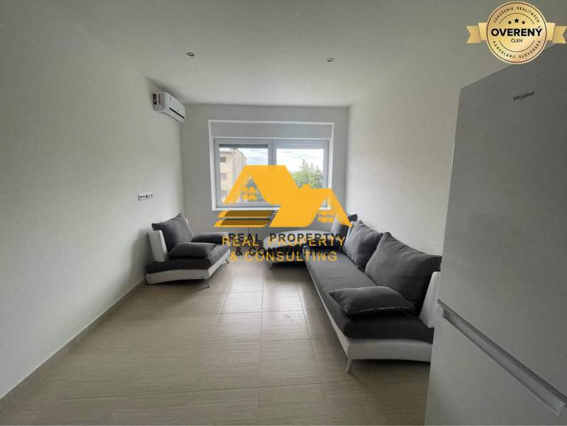 Prenajmem zariadený 3 izbový byt v Nových Zámkoch - Obývacia izba v 3-izbovom byte s dvoma sivými pohovkami a bielou chladničkou.