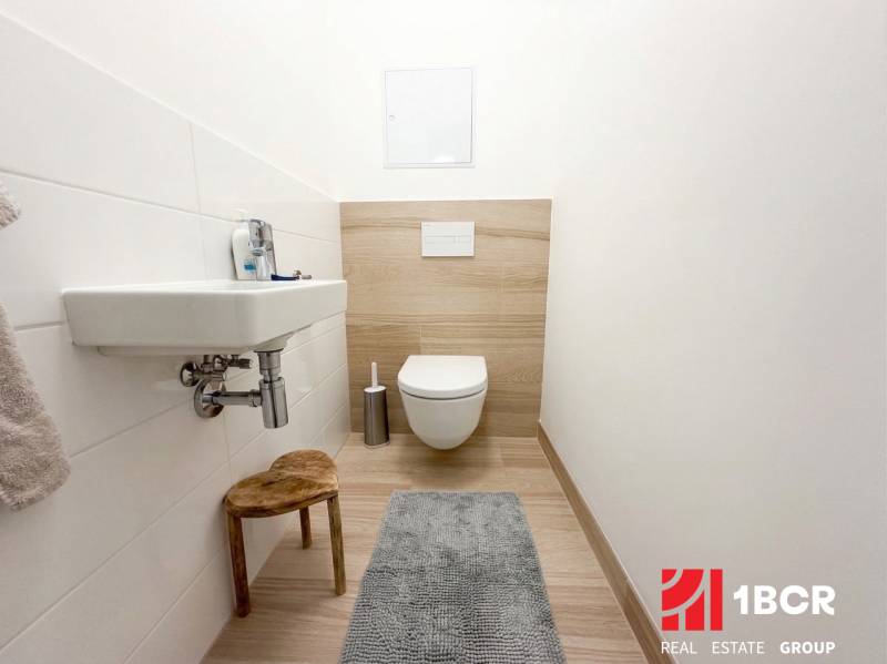 KOMPLETNE ZARIADENÝ 3-IZB. BYT, NOVOSTAVBA STEIN, BLUMENTÁLSKA UL. - Kúpeľňa s umývadlom, závesným WC a podlahou s dreveným dekorom v 3-izbovom byte.