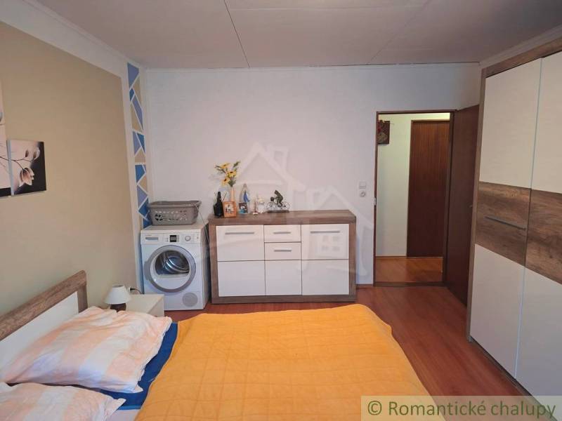 Veľkorysý 10-árový pozemok, slnečná nehnuteľnosť, priestranné bývanie  - Spálňa v rodinnom dome s práčkou, skriňou a dekorom drevenej podlahy.