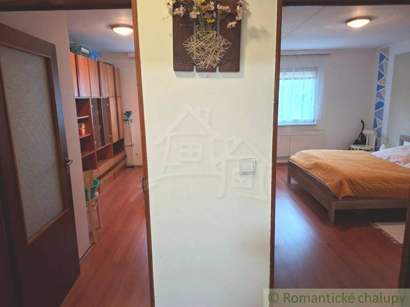 Veľkorysý 10-árový pozemok, slnečná nehnuteľnosť, priestranné bývanie  - Interiér rodinného domu s podlahou s dreveným dekorom, spálňa a úložný priestor.