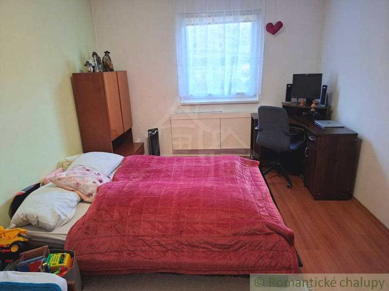 Veľkorysý 10-árový pozemok, slnečná nehnuteľnosť, priestranné bývanie  - Spálňa v rodinnom dome s posteľou, pracovným stolom a podlahou s dreveným dekorom.