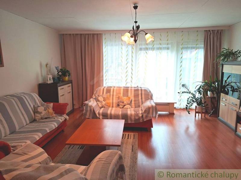 Veľkorysý 10-árový pozemok, slnečná nehnuteľnosť, priestranné bývanie  - Obývacia izba v rodinnom dome s podlahou s dreveným dekorom, svetlom a pohovkami.