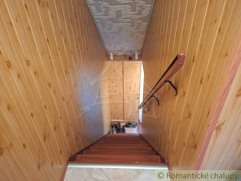 Veľkorysý 10-árový pozemok, slnečná nehnuteľnosť, priestranné bývanie  - Interiér rodinného domu s dreveným obložením stien a schodiskom s dreveným dekorom.